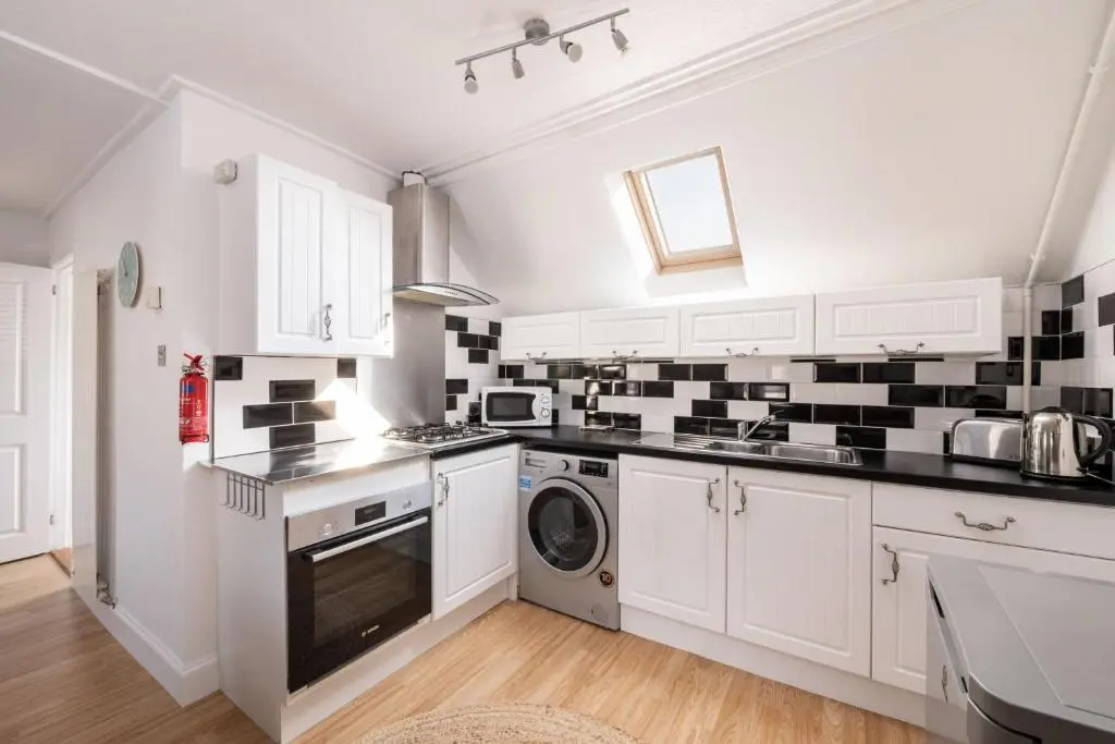 a white kitchen with black and white tiles on the wall at Fishermans Rest in Lossiemouth