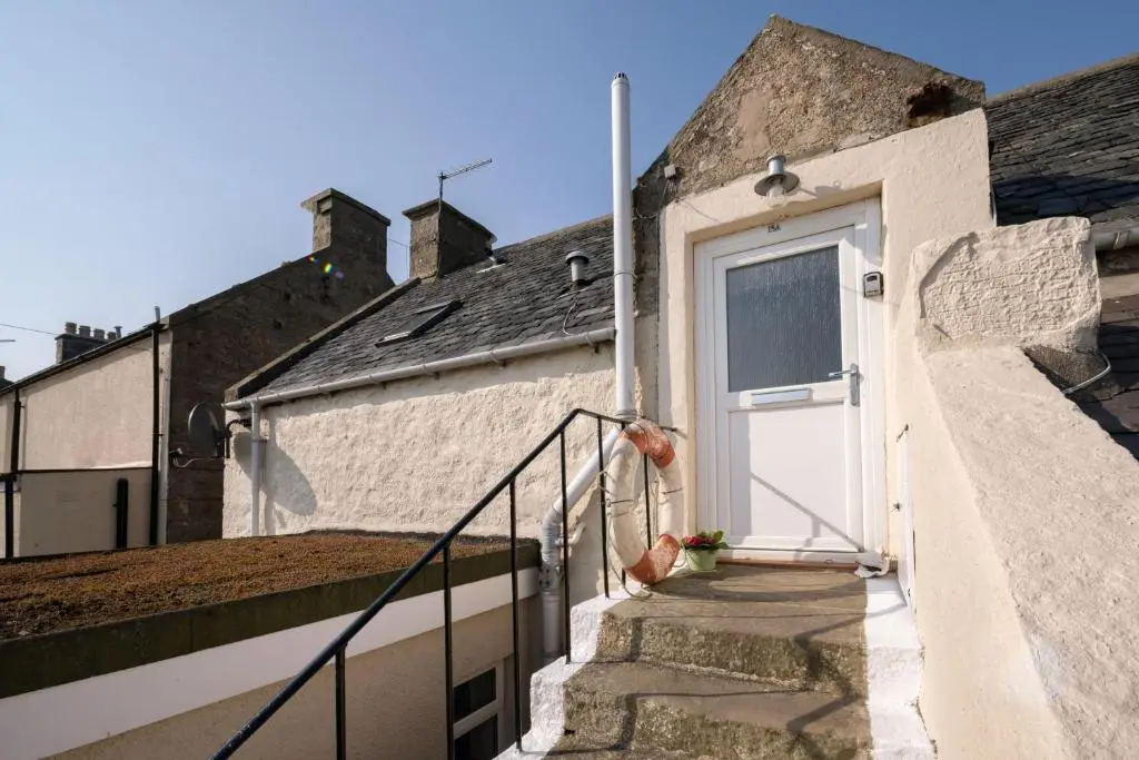 a white door on a white building with stairs at Fishermans Rest in Lossiemouth