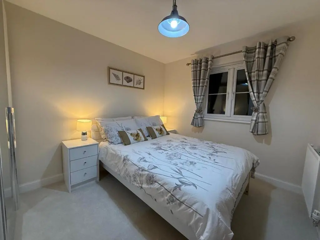 a bedroom with a bed and a nightstand and a window at Loch Ness Hideaway in Inverness