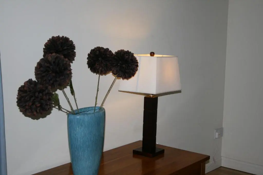 a blue vase with flowers and a lamp on a table at BCC Loch Ness Cottages in Drumnadrochit