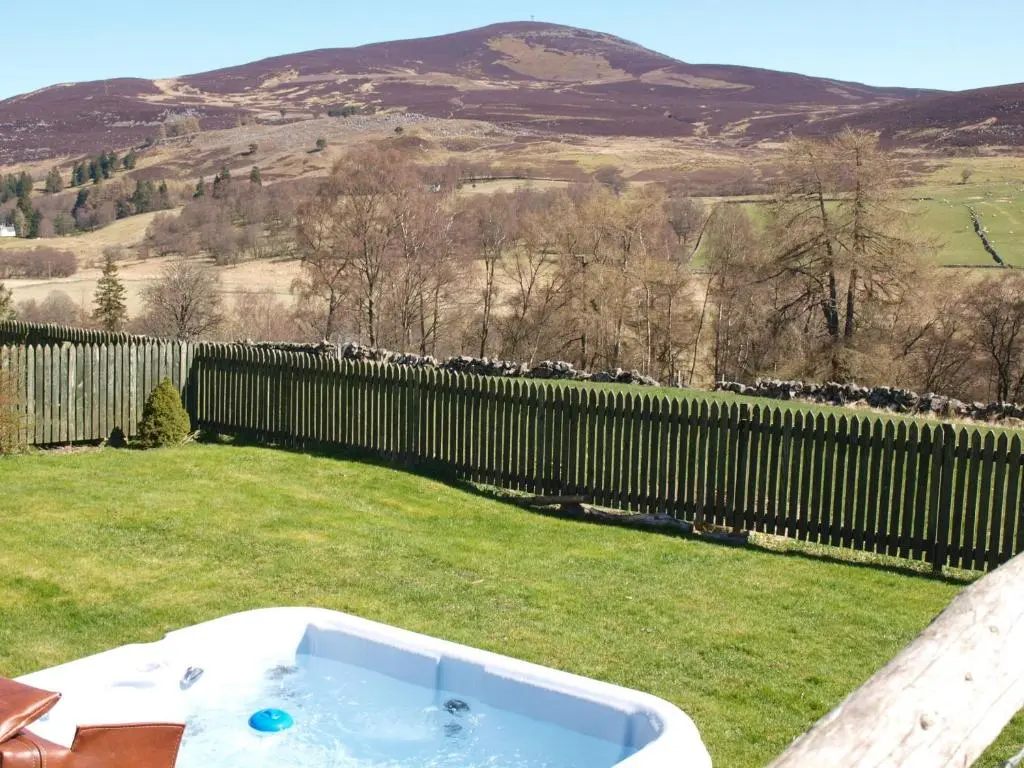 a bath tub in a yard with a fence at Groose Hoose in Glenshee