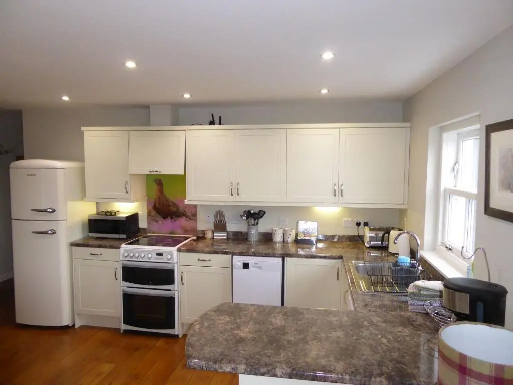 a kitchen with white cabinets and a white refrigerator at Groose Hoose in Glenshee