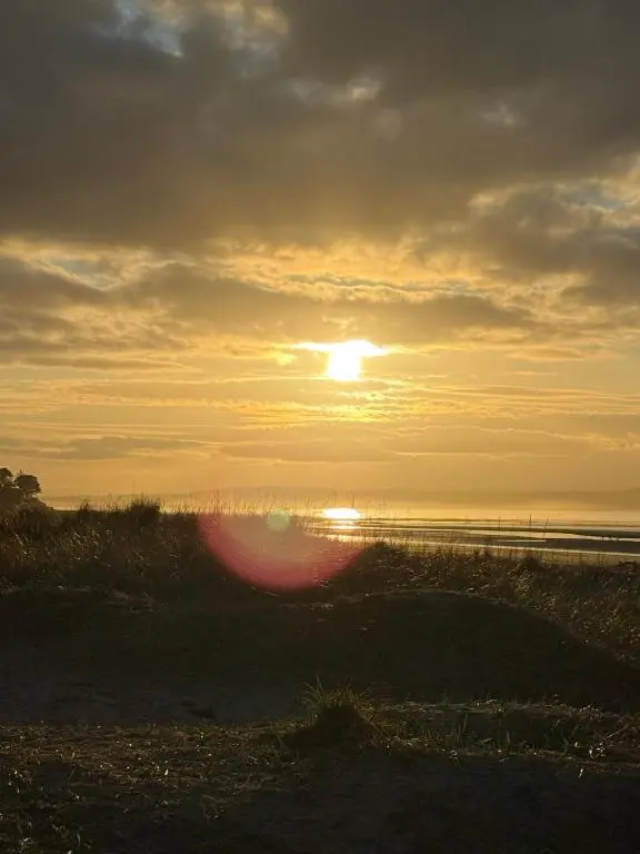 a sunset on the beach with the sun setting at Agnes Place in Nairn