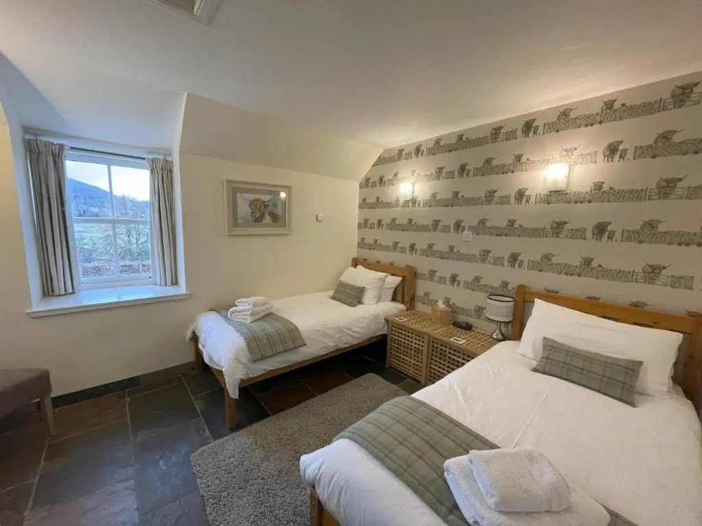 a bedroom with two beds and a window at Coo Shed in Glenshee