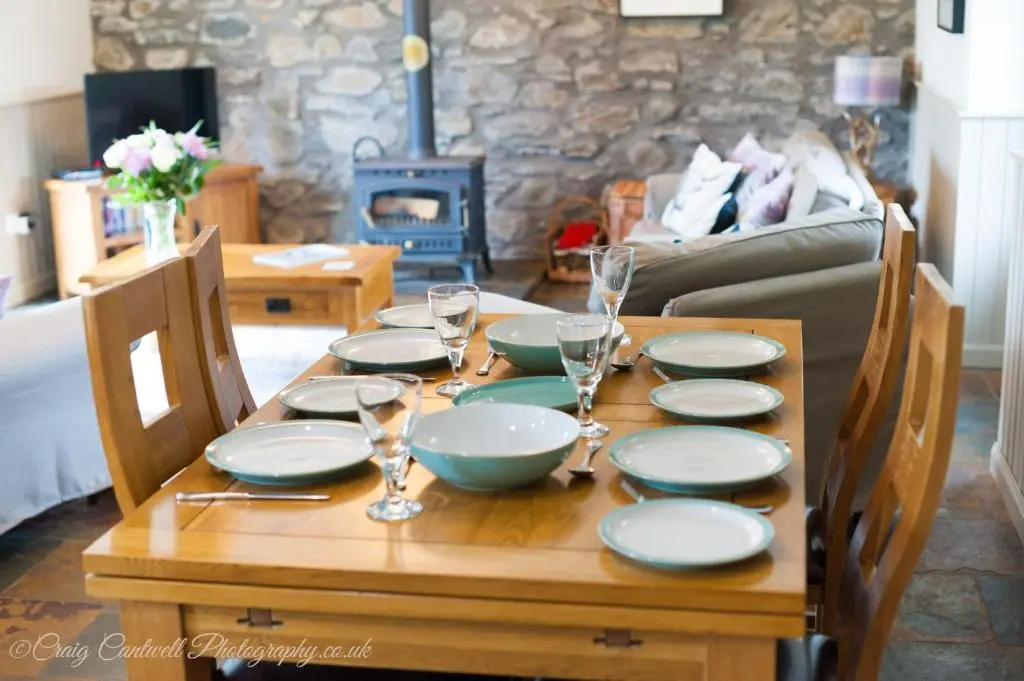 a wooden table with plates and wine glasses on it at Coo Shed in Glenshee