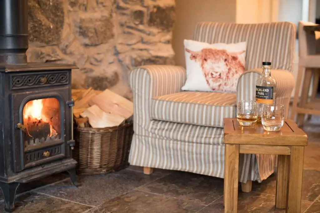 a living room with a chair and a wood stove at Smiddy Cottage in Glenshee