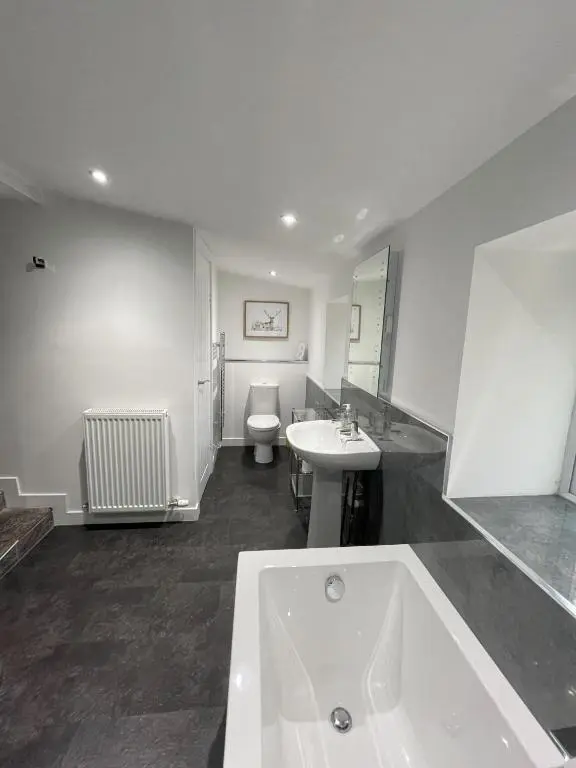 a bathroom with a tub and a toilet and a sink at Smiddy Cottage in Glenshee