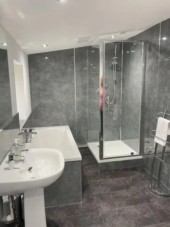a bathroom with a shower and a sink and a tub at Smiddy Cottage in Glenshee