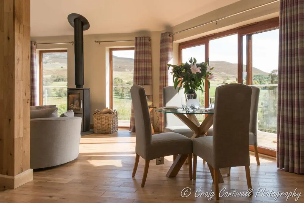a dining room with a glass table and chairs at Scots Pine Treehouse in Glenshee