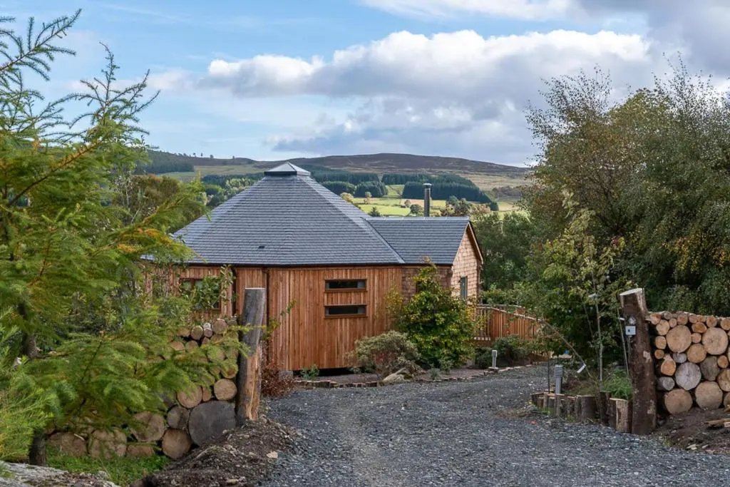 a wooden barn with a fence and a driveway at Silver Birch Treehouse in Glenshee