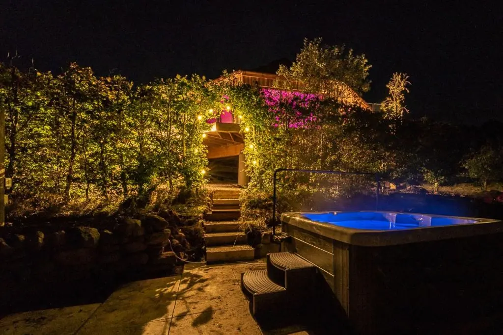 a house with a jacuzzi in the yard at night at Silver Birch Treehouse in Glenshee
