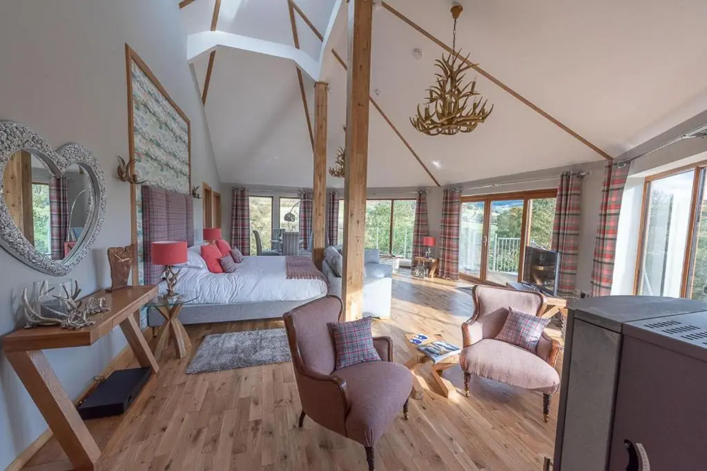 a living room with a bed and a living room with windows at Silver Birch Treehouse in Glenshee