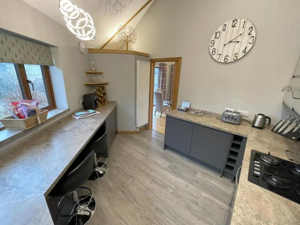 a kitchen with a large clock on the wall at Silver Birch Treehouse in Glenshee