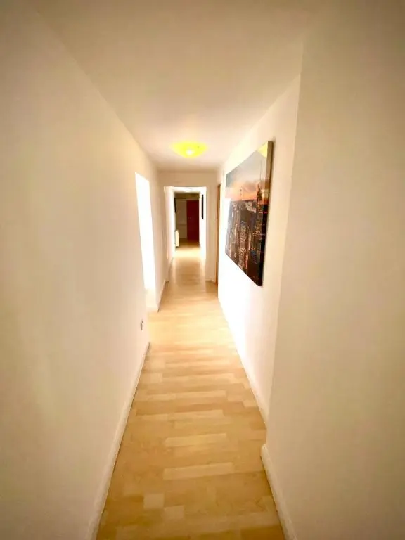 a hallway with white walls and a wooden floor at Dolphin Bay Suites in Ardersier