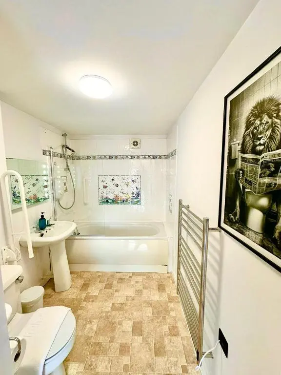 a bathroom with a toilet and a tub and a sink at Dolphin Bay Suites in Ardersier