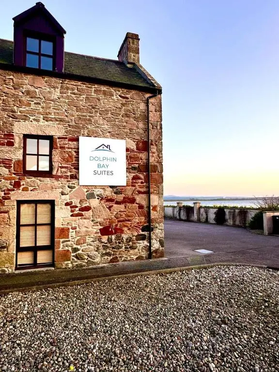 a brick building with a sign on the side of it at Dolphin Bay Suites in Ardersier