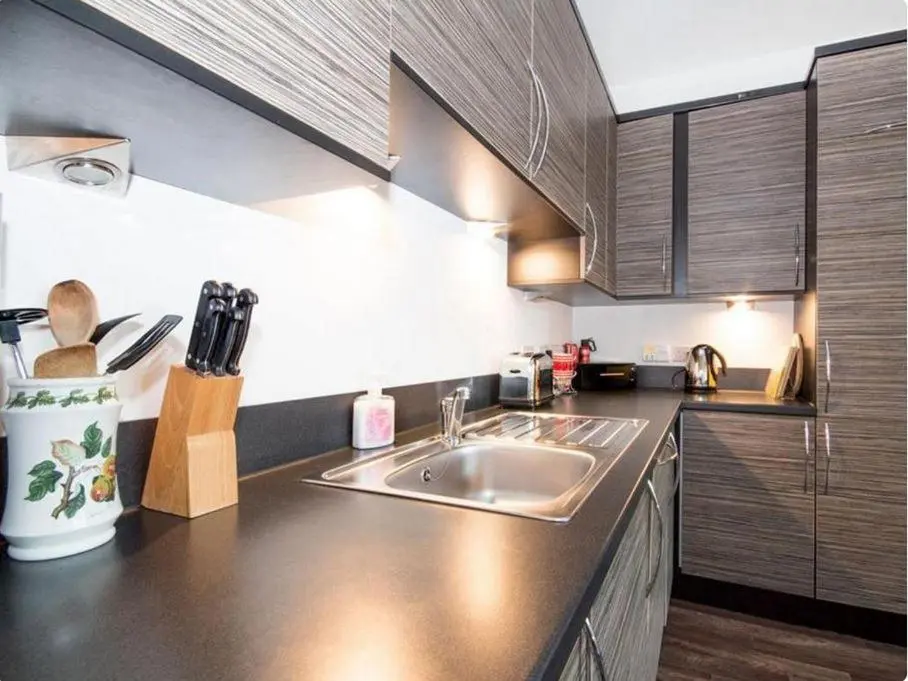 a kitchen with a sink and wooden cabinets at Mercury Holiday Home 1 Bedroom 7 Westercraigs Apartment -Free Parking in Inverness