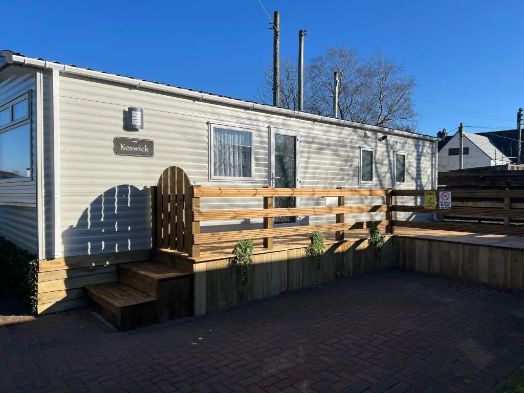 a trailer with a fence and a wooden bench at The Highland Getaway 43 in Boat of Garten