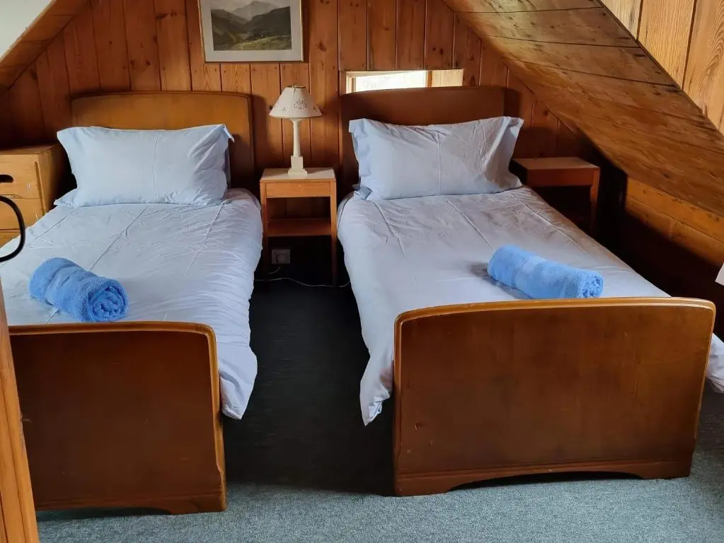 two beds in a room with blue pillows at Strathnoon in Inverness