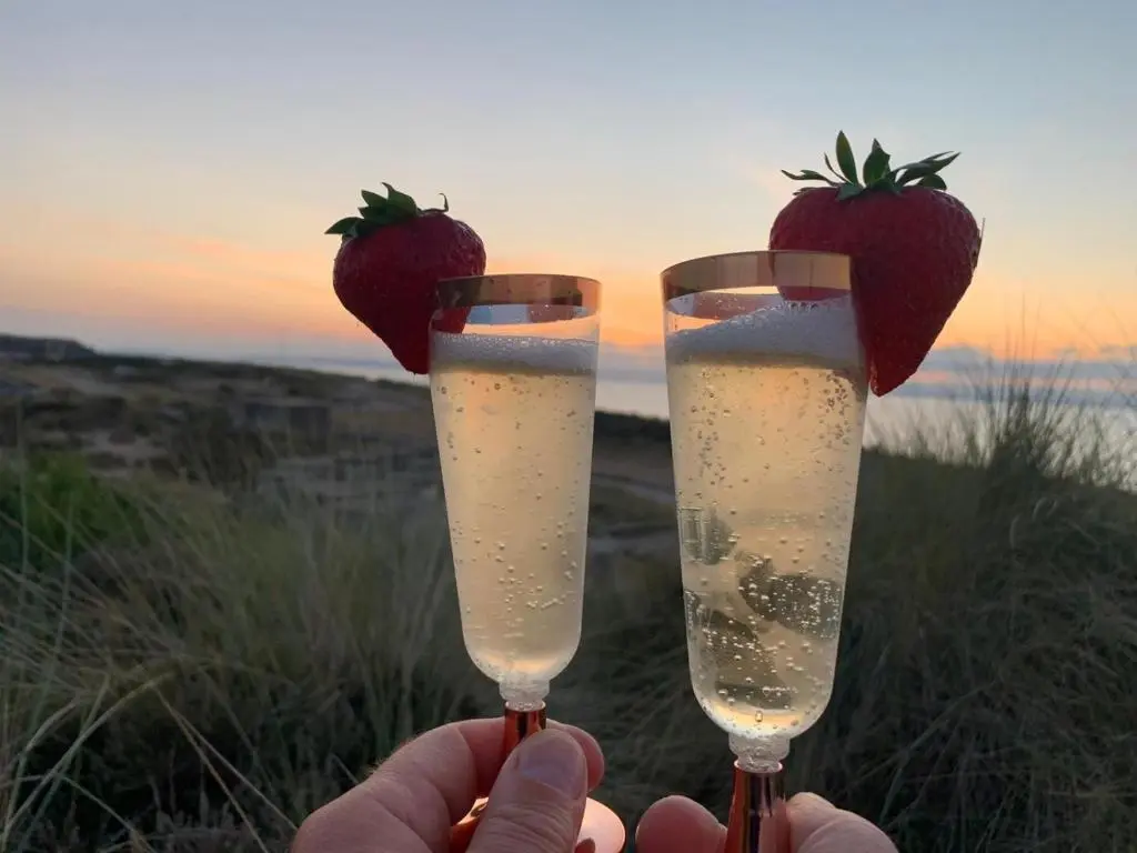 a person holding two champagne glasses with strawberries in them at Modern Eco-Lodges near Findhorn Beach in Findhorn