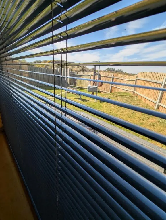 a window with blue blinds looking out at a fence at Modern Eco-Lodges near Findhorn Beach in Findhorn