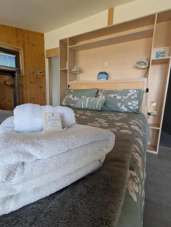 a bedroom with a large bed with towels on it at Modern Eco-Lodges near Findhorn Beach in Findhorn