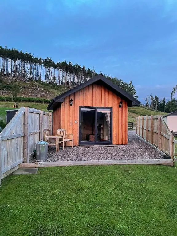 a wooden shed with a table and a fence at The Wee Knoll in Invergarry