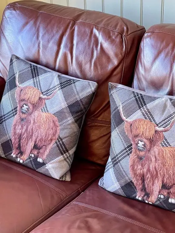 a couch with two pillows with a goat on it at The Wee Knoll in Invergarry