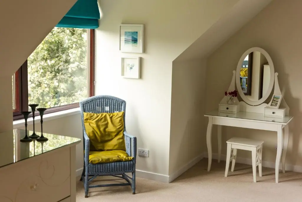 a dressing room with a chair and a mirror at Caledonian View House in Dalneigh