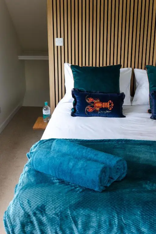 a bed with a blue blanket and pillows on it at Caledonian View House in Dalneigh