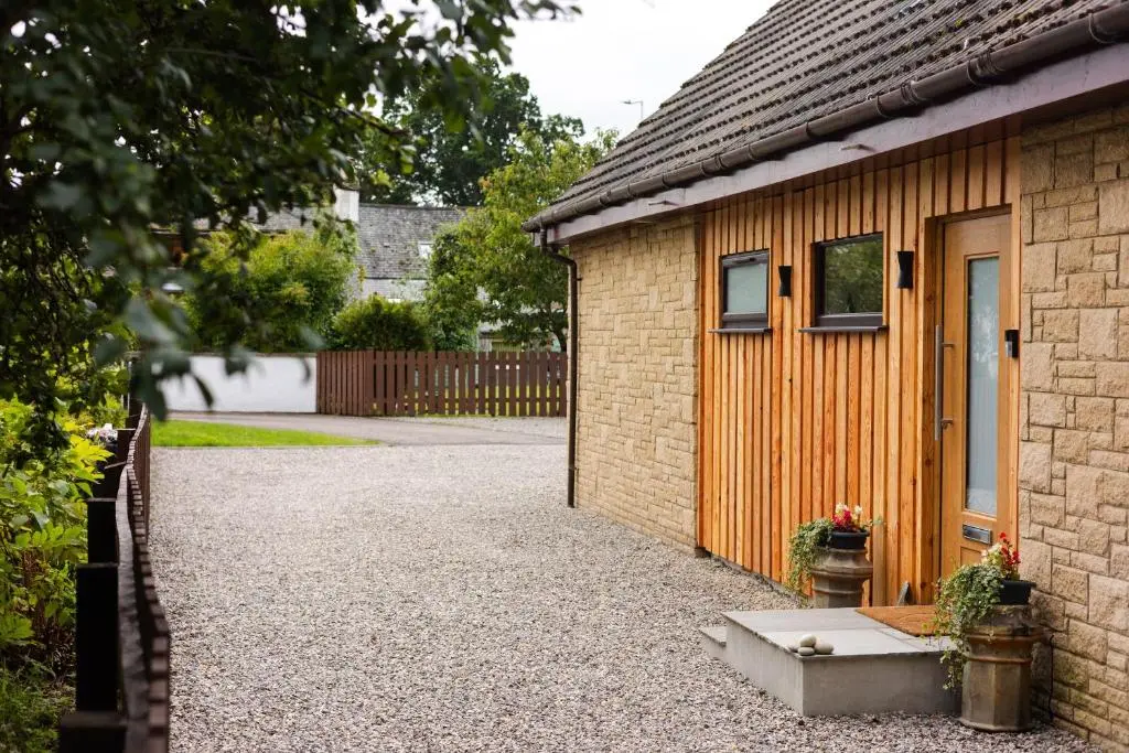 a house with a gravel driveway next to a building at Caledonian View House in Dalneigh