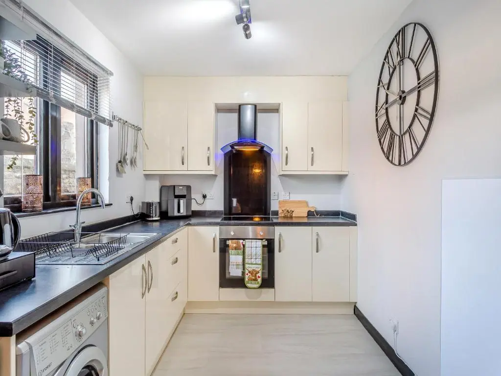 a kitchen with white cabinets and a clock on the wall at Failte Luxury Apartment in Inverness