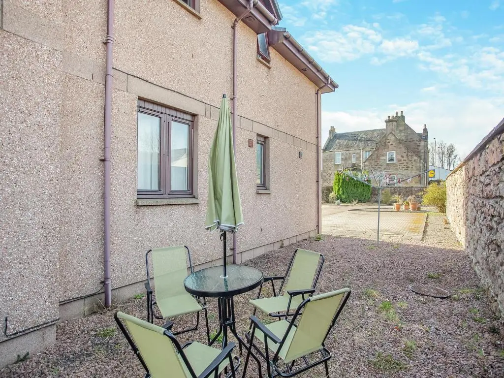 a patio with a table and chairs and an umbrella at Failte Luxury Apartment in Inverness