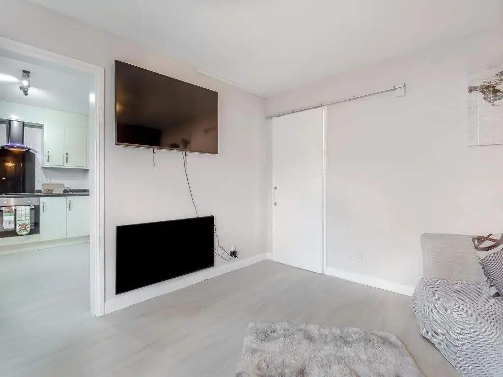a white living room with a tv and a couch at Failte Luxury Apartment in Inverness