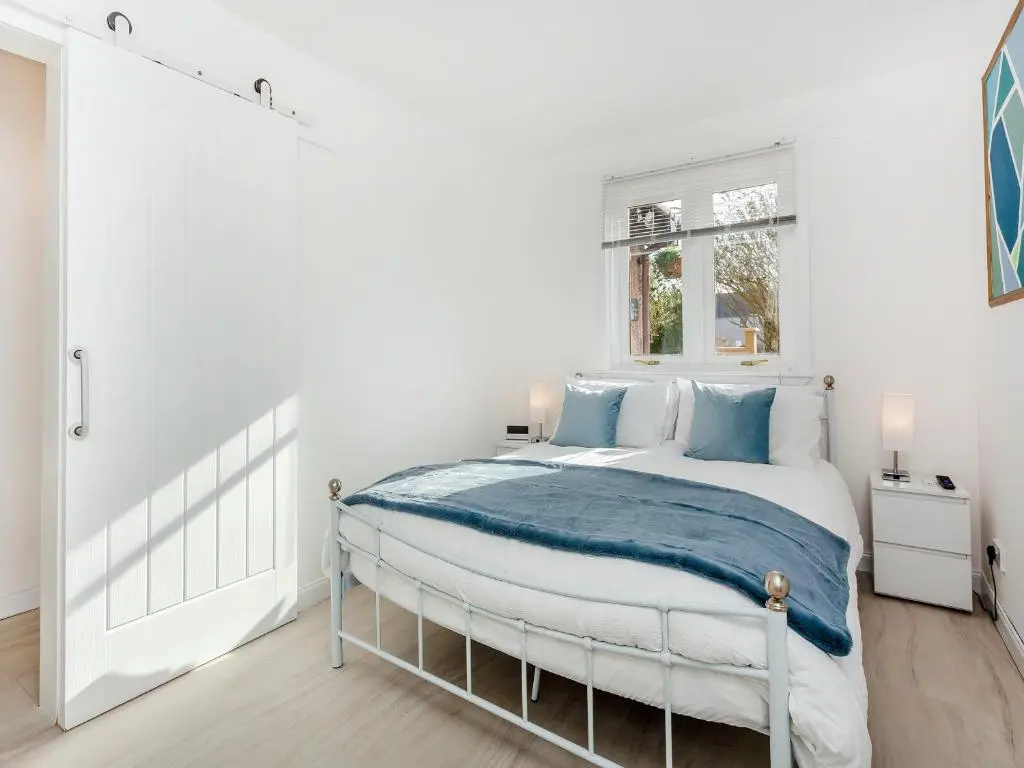 a white bedroom with a bed and a window at Failte Luxury Apartment in Inverness