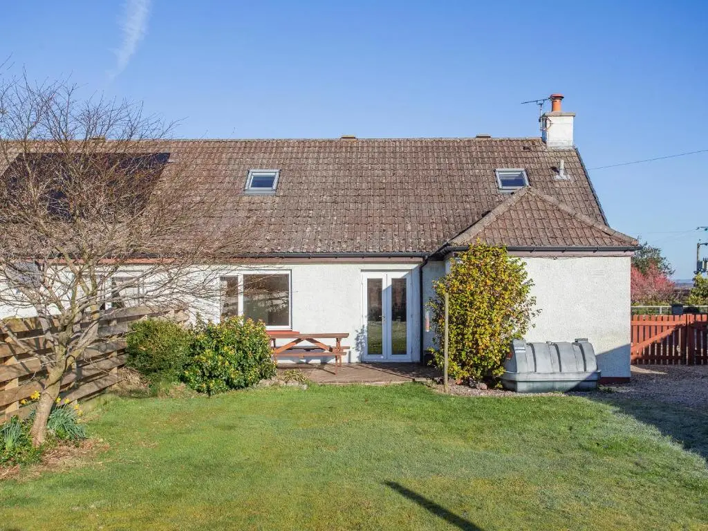 a house with a picnic table and a bench in the yard at The Cherry Tree in Cawdor