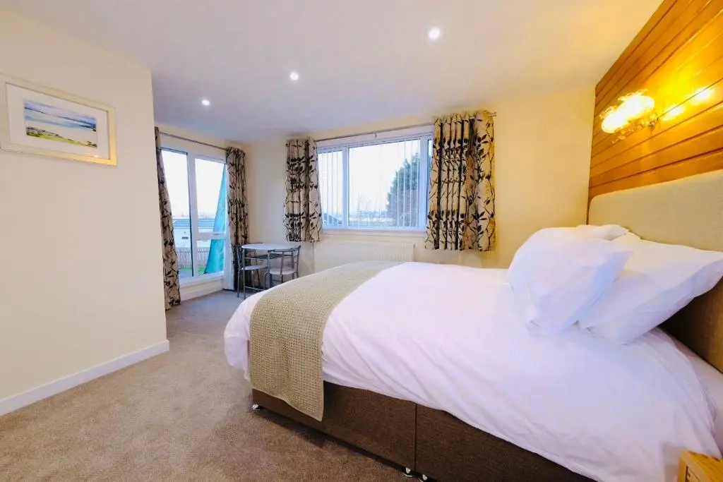 a bedroom with a large white bed and windows at Suilven Cottage in Tain