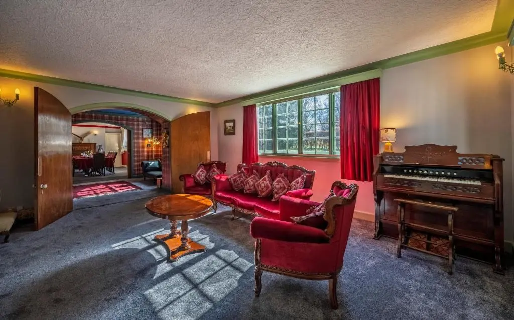 a living room with a red couch and a piano at Finest Retreats - White House Retreat in Cornhill
