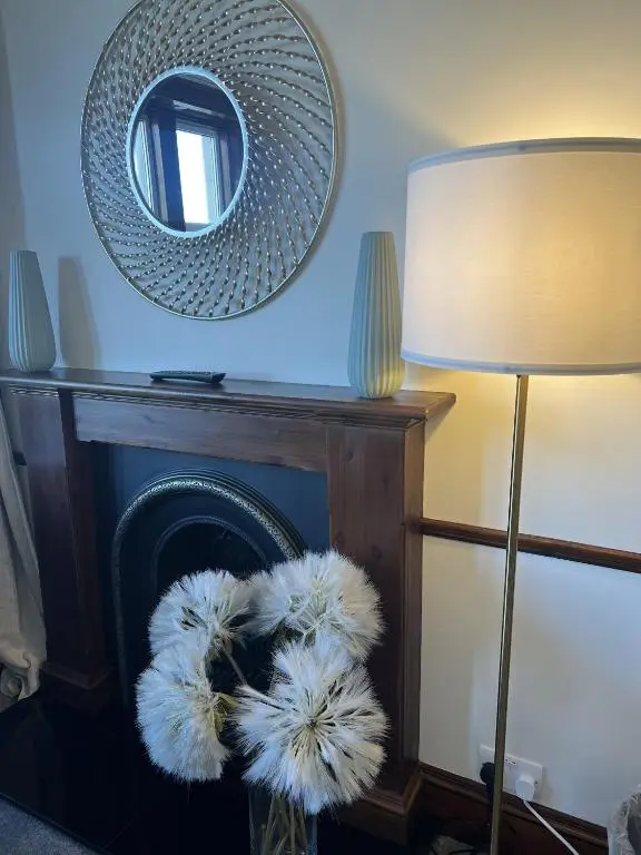 a mirror over a fireplace next to a lamp at Springfield guest house in Tain