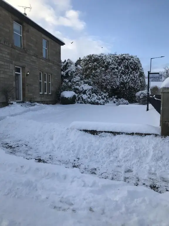a driveway covered in snow next to a house at Springfield guest house in Tain