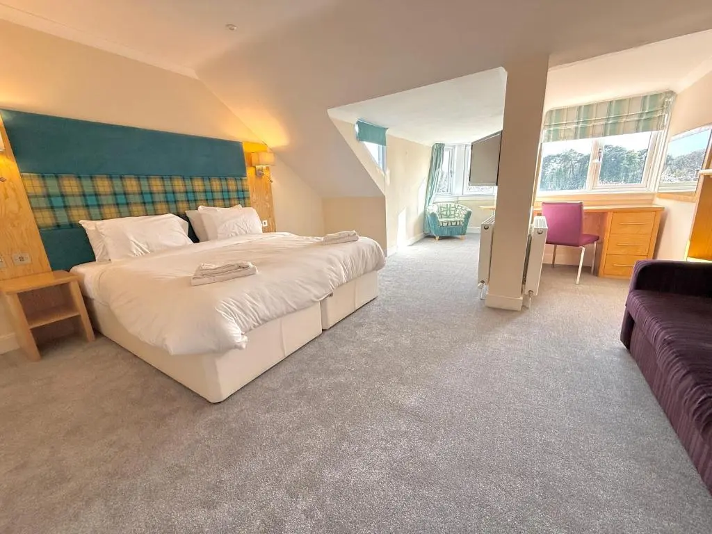 a bedroom with a large bed and a couch at Seabank House Hotel in Nairn