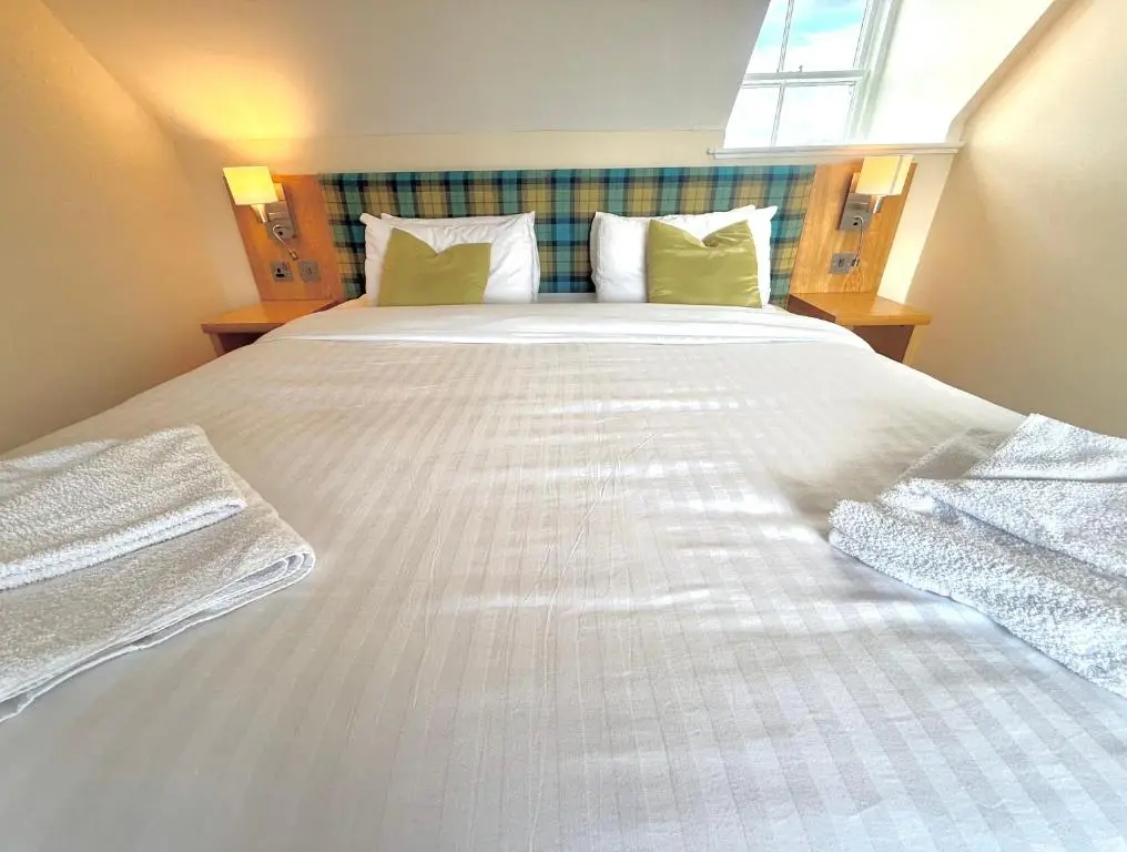 a large white bed in a room with a window at Seabank House Hotel in Nairn