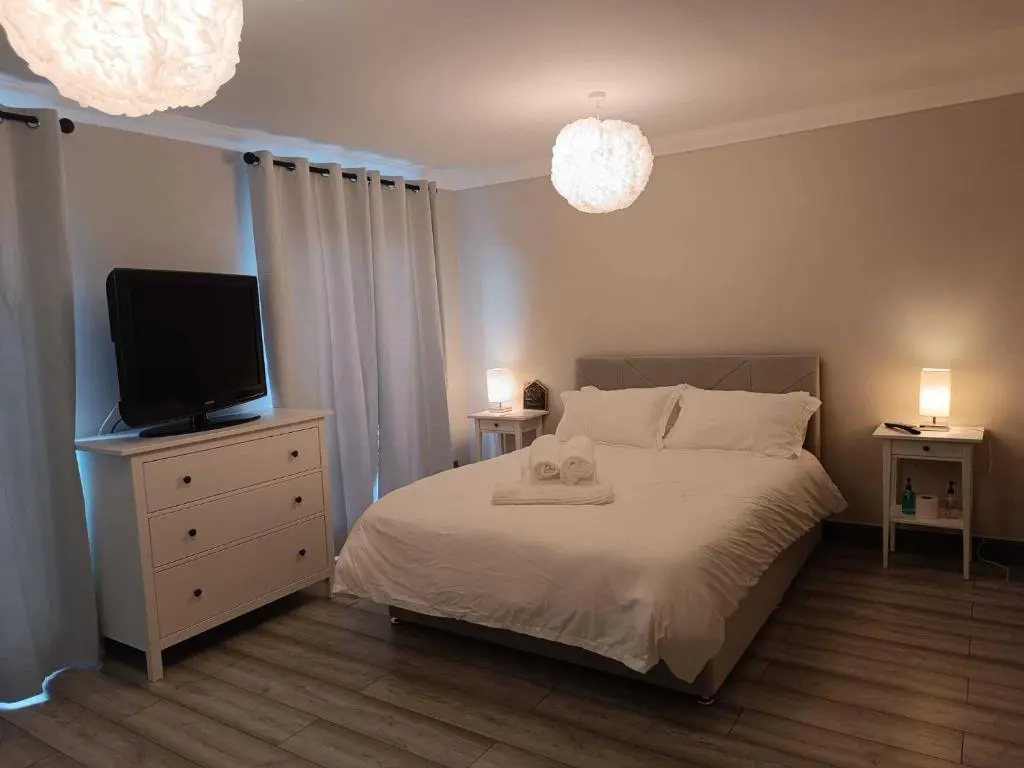 a bedroom with a bed and a flat screen tv at Woodgrove Holiday Homes in Inshes