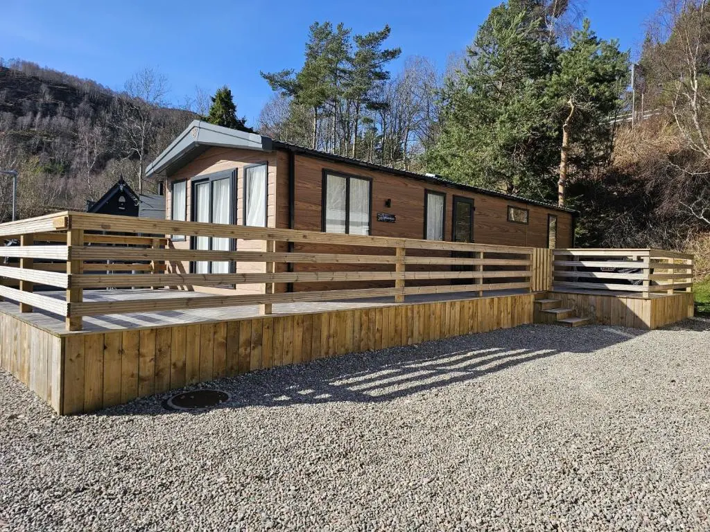 a cabin with a wooden fence in front of it at Monash in Aviemore