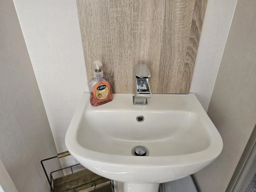 a white sink with a bottle of soap on it at Monash in Aviemore
