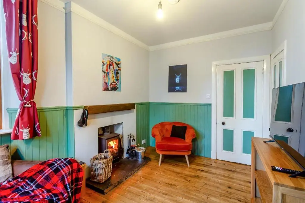 a living room with a red chair and a fireplace at 3 Bed in Huntly oc-g31733 in Huntly