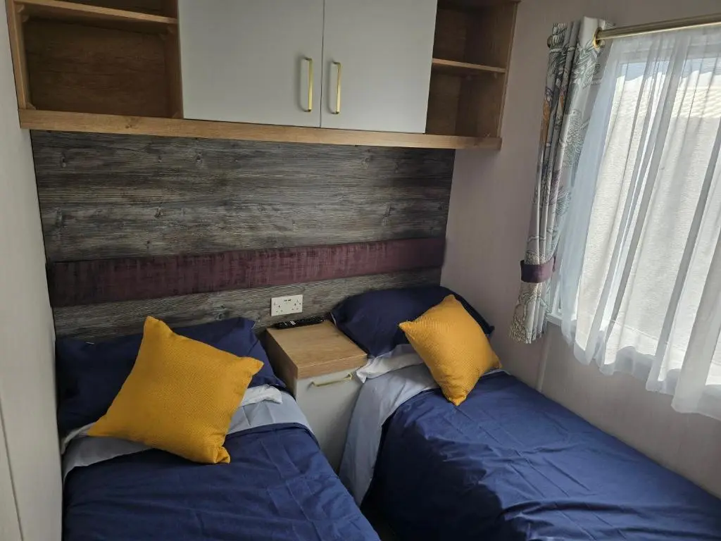 two beds in a small room with blue and yellow pillows at 3 Bed-Sleeps 8-Free Parking-5 Min to Beach in Dornoch