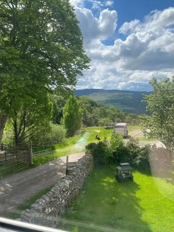 a stone wall with a picnic table in the grass at The old Farmhouse Minutes from lochness in Drumnadrochit