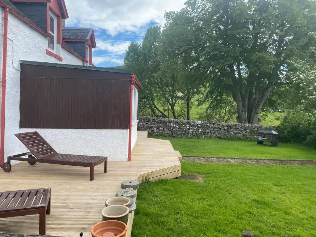 a wooden deck with a bench and a fence at The old Farmhouse Minutes from lochness in Drumnadrochit