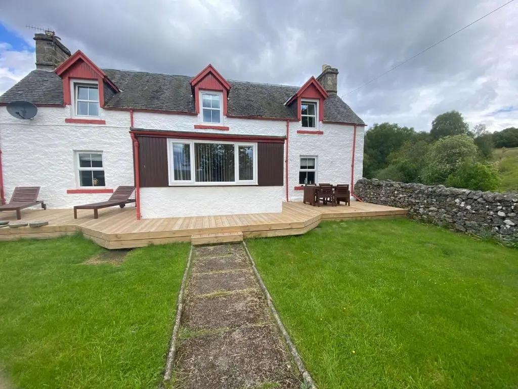 a house with a large yard with a wooden deck at The old Farmhouse Minutes from lochness in Drumnadrochit